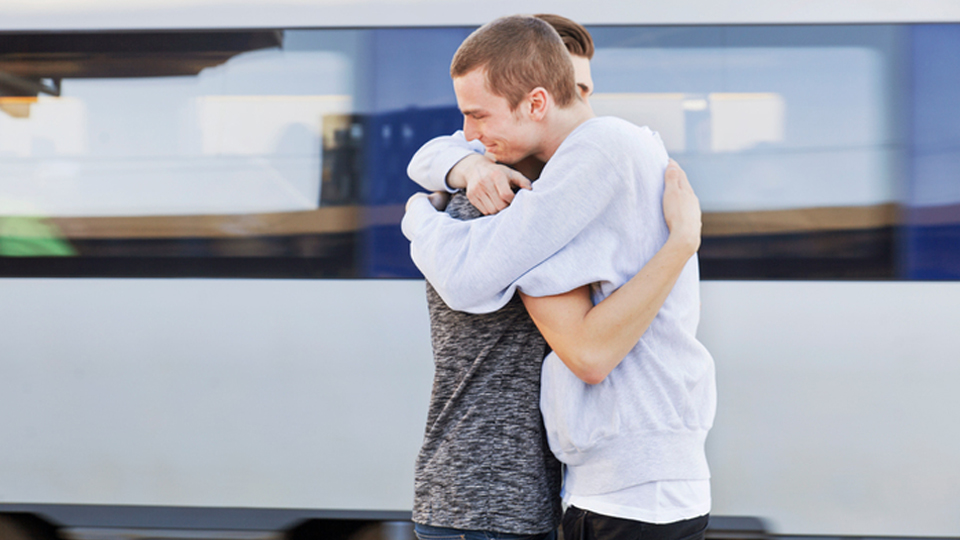 Två personer som kramar om varandra vid tåget